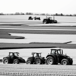 Black and white line art of a tractor plowing a field, featuring simple outlines and blank fill areas, ideal for coloring book enthusiasts.